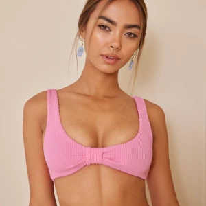 Rosa ribbad bikiniöverdel - Säljer en superfin rosa bikiniöverdel med ribbad textur. Den har en söt knytdetalj framtill som ger en extra touch. Perfekt för sommarens alla badäventyr!