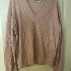 Beige stickad tröja från Marimekko - Säljer en superfin ljusrosa ull tröja från Marimekko. Den har ett snyggt rutmönster och en djup v-ringning. Perfekt för höst och vinter, och den är riktigt mysig att ha på sig. Tröjan har långa ärmar och ribbade kanter som ger en skön passform. Passar perfekt till både jeans och kjol! Använd men i mycket bra sy