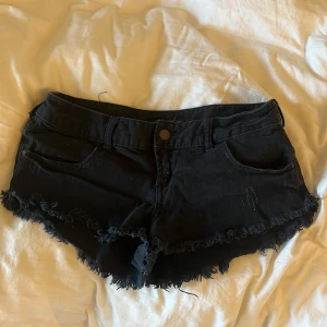 Svarta lågmidjade shorts - Lågmidjade svarta jeansshorts med små rivdetaljer från Billabong som tyvärr är förstora på mig.