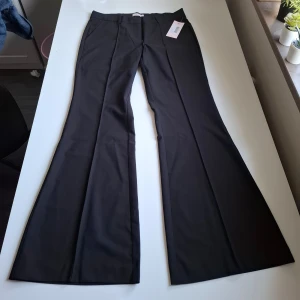 Lågmidjade kostymbyxor - Svarta flared kostymbyxor från Nelly. Aldrig använda och prislapp kvar. Säljer p.ga fel storlek.  waist - 41 inseam - 81