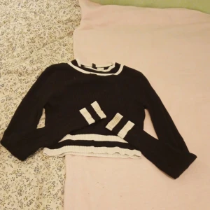Svart och vit ribbad tröja från H&M - Säljer en svart och vit ribbad tröja från H&M. Tröjan har långa ärmar och en croppad design med randiga detaljer vid ärmslut och nederkant. Perfekt för en stilren look!