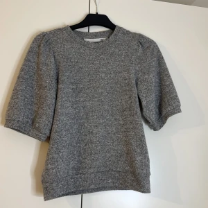 Grå tröja med puffärmar - Säljer en stilren grå tröja från Lager 157 med puffiga trekvartsärmar. Perfekt för en chic och avslappnad look. Tröjan har en rund halsringning och är gjord i ett mjukt material som känns skönt mot huden.