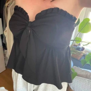 Svart bandeau top - Svart bandeau top i fint skick. Man kan knyta en rosett framtill för extra detaljer, storlek S