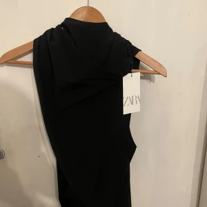Svart ärmlös topp från Zara - Snygg svart ärmlös topp från Zara  i storlek S med knytning i halsen. Perfekt för en stilren look. Toppen har en elegant design som passar till många tillfällen, den är ny med prislapp och aldrig använd! 