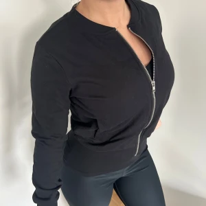 Svart bomberjacka med dragkedja - Snygg svart kofta/tröja med dragkedja framtill. har en klassisk design med långa ärmar och ribbade muddar vid ärmslut och nederkant🖤