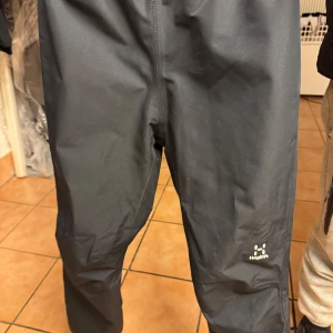 Svarta byxor från Haglöfs - Snygga svarta byxor från Haglöfs, perfekta för utomhusaktiviteter. Byxorna har en enkel design med elastisk midja för extra komfort. Tillverkade i ett slitstarkt material som passar bra för olika väderförhållanden.