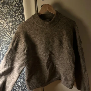 Brun stickad tröja - Mysig brun stickad tröja med rund hals och långa ärmar. Perfekt för kyliga dagar och ger en avslappnad stil. Passar bra till jeans eller kjol.