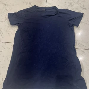 Mörkblå t-shirt från 157 - Säljer en mörkblå t-shirt från 157 i 100% bomull. Den har en klassisk design med korta ärmar och rund hals. Perfekt för en avslappnad stil.