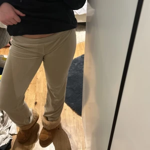 Beige byxor - Snygga beige byxor med en tight passform. De är lågmidjade och har en stilren design som passar perfekt för en avslappnad look. Materialet ser mjukt och bekvämt ut, vilket gör dem idealiska för vardagsbruk.