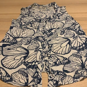 Jättefin blåvit fjärils-blus från Boomerang 🦋🦋 - Jättegullig blåvit blus med fjärils-mönster! Perfekt för att använda under en kavaj eller på sommardagar då blusen inte har några ärmar!☀️ Den är använd en gång så nästan i helt nytt skick ⭐️⭐️ Den har inga täcken på skador! 