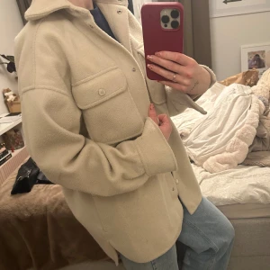 Beige jacka H&M - Säljer en snygg beige vår jacka från H&M. Den har en avslappnad passform med knappar framtill och två bröstfickor med lock. Perfekt för lager-på-lager-stil och passar till många olika outfits. Den är ganska tjock i materialet, har en till likadan super fin och slutsåld på H&M. XS storlek
