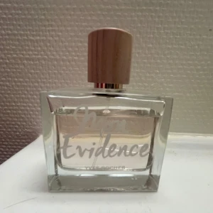 Mon Evidence från Yves Rocher - Mon Evidence från Yves Rocher är en fruktig och blommig parfym med noter av mandarin, apelsinblomma och bergamott. Hjärtat består av damascenerrosor, päron, persika och jasmin, medan basen har inslag av patchouli och vanilj. Flaskan är elegant med en träliknande kork. Använd men mycket kvar. Obruten förpackning innehåller 50 ml. Säljer då den inte föll mig i smaken