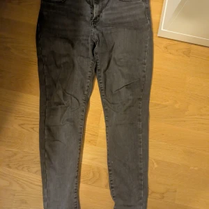 Levis Grå super skinny jeans - Snygga grå super skinny jeans med hög midja. Perfekta för en stilren look. De har en dragkedja och knapp framtill.