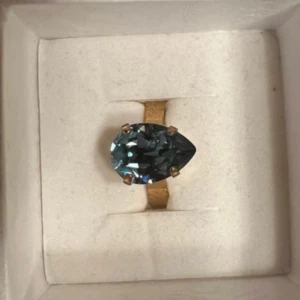 Ring med blå sten från Caroline Svedbom - Elegant ring från Caroline Svedbom med en stor, droppformad blå sten infattad i en guldfärgad ring. 💖 inköpt för 595kr💘