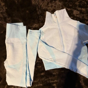 Ljusblått träningsset - Snyggt träningsset med en ribbad textur. Setet består av en jacka med dragkedja och matchande leggings. Använt 2 gånger 