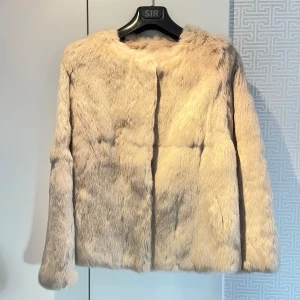 Beige/vit  pälsjacka från Nature Collection - Säljer en elegant beige pälsjacka från Nature Collection. Jackan har en mjuk och lyxig känsla med långa ärmar och en stilren design. Perfekt för att hålla sig varm och snygg under kyliga dagar. 🧥✨