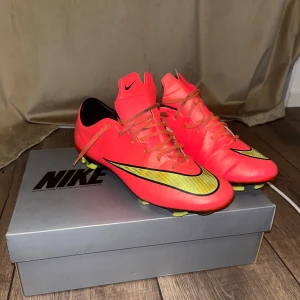 Nike mercurial x fg elite red/yellow storlek 41/26cm - Snygga röda fotbollsskor från Nike med svarta och gula detaljer. Skorna har snörning och är designade för optimal prestanda på planen. Perfekta för den som vill sticka ut med stil och funktion.