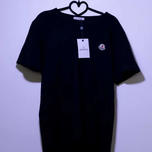 Svart t-shirt från Moncler - Snygg svart t-shirt från Moncler med korta ärmar och en liten broderad logga på bröstet. Perfekt för en stilren look. 🖤Oanvänd.