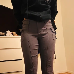 Grå cargopants - Snygga grå cargopants med hög midja och praktiska fickor på sidorna. Perfekta för en avslappnad stil med en touch av funktionalitet. Passar bra till en hoodie eller t-shirt.