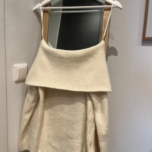 Cremefärgad stickad offshoulder tröja - Säljer en mysig beige stickad tröja med offshoulder-design. Tröjan har långa ärmar och en bred krage som ger en stilren look. Perfekt för kyligare dagar och att mysa i hemma. Passar bra till jeans eller kjol för en avslappnad stil. Använd och tvättad 2 gånger. Inköpt i december 2024 från H&M. 