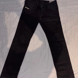 Svarta jeansbyxor - Snygga svarta Diesel jeansbyxor med klassisk femficksdesign och knappgylf. Perfekta för en stilren look. Passar bra till både vardag och mer uppklädda tillfällen.