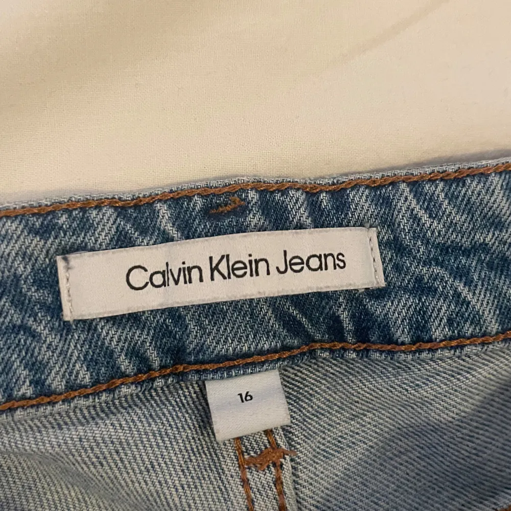 Snygga blå jeans från Calvin Klein med en klassisk femficksdesign. De har en normal passform och är perfekta för en avslappnad stil. Jeansen har en knappgylf och är tillverkade i ett slitstarkt denimtyg. Jeansen är i storlek 16years och har en defekt på knät därav billigt pris. Om du har någon fundering är det bara att höra av sig. Mvh Levi!. Farkut & Housut.