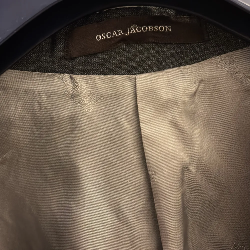 Elegant grå kavaj från Oscar Jacobson med klassisk design. Kavajen har två knappar framtill och fickor på sidorna. Perfekt för en stilren look.. Puvut & Bleiserit.