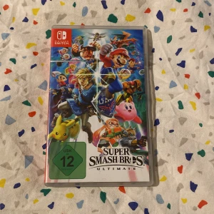 Super Smash Bros. Ultimate för Nintendo Switch - Säljer spelet Super Smash Bros. Ultimate för Nintendo Switch. Omslaget visar flera kända karaktärer som Mario, Link och Pikachu. Perfekt för fans av actionfyllda multiplayer-spel. USK 12-märkning.