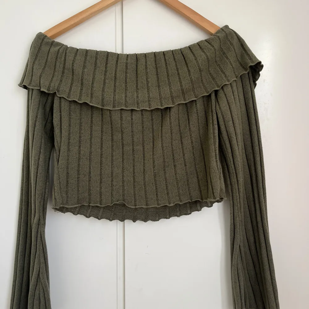 Snygg olivgrön offshoulder-tröja med ribbad struktur och långa ärmar. Perfekt för en trendig look med sin croppade design. . Neuletakit & Villapaidat.