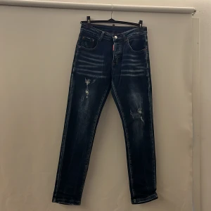 Mörkblå jeans från Dsquared2 - Säljer nu mina riktigt snygga blåa jeans ifrån Dsquared2, de säljes för de aldrig används. Byxorna är aldrig använda alltså i nyskick. Storleken är Size 38/44 och passar dig som är från 168cm-175cm, passar även dig som är lite längre än det. Om ni har frågor är det bara att ställa😀