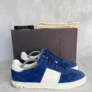 Valentino Flycrew - Snygga sneakers i Marinblå mocka med vita detaljer från Valentino Garavani. Skorna har en klassisk design med snörning och en vit sula. Perfekta för en stilren look. Topp skick, som nya!💯