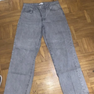 Grå jeans från Ginatricot - Säljer ett par grå jeans med låg midja från Ginatricot i storlek 38. De har en klassisk femficksdesign och knappar i gylfen. Den har endast används 2 gånger 