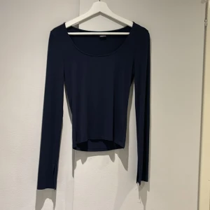 Mörkblå långärmad topp från Gina Tricot - Säljer en stilren mörkblå långärmad topp från Gina Tricot. Toppen har en enkel design med rund halsringning och är tillverkad i ett mjukt material som ger en skön passform. Perfekt för en avslappnad look.