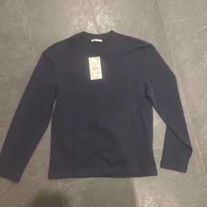 Helt ny mörkblå långärmad tröja från Zara - Säljer en stilren mörkblå långärmad tröja från Uniqlo. Perfekt för en minimalistisk look och passar bra till alla typer av byxor. Tröjan har en enkel design utan mönster. Passar både M och S. 