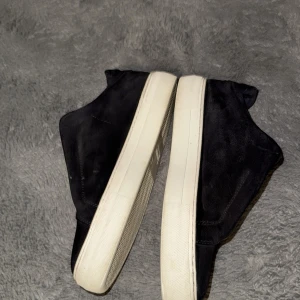 Arigato skor - Snygga svarta sneakers från Axel Arigato med vit sula. Skorna har en stilren design med diskret logga på sidan. Perfekta för en avslappnad och trendig look. Skorna kanske bara behöver en snabb mocka tvätt för att se helt nya ut igen bara. Stilrena annars köptes här på Plick men tyvärr passade dom inte mig då jag har 45 tänkte 43 skulle passa. Dem passar även 42. Pris går att diskutera vid snabb affär endast.