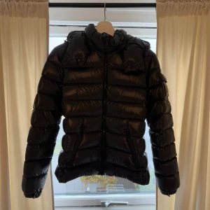 Moncler Maya - Moncler Maya, svart – storlek 2  Säljer min Moncler Maya i svart, storlek 2. Jackan är i nästan nyskick, då jag har använt den max fem gånger. Inga skador, fläckar eller tecken på slitage – ser i princip ut som ny. Jackan har en luva som går att ta både av och på.  En stilren och lyxig dunjacka som är både lättviktig och varm, perfekt för kyliga dagar. Säljes endast eftersom jag inte använder den.  Nypris ligger på 15 000 + kr Pris kan diskuteras.