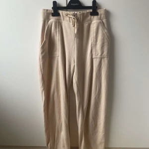 Beige mjukisbyxor från Juicy Couture - Säljer ett par beige mjukisbyxor från Juicy Couture. Byxorna har en bekväm passform med snörning i midjan och praktiska fickor framtill. Endast använda en gång🫶