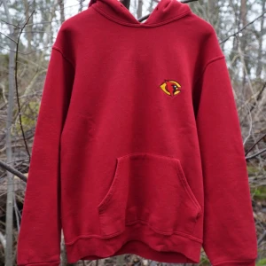 Röd hoodie med tryck - Säljer en röd hoodie med gul logga på bröstet och texten 'BCHS' på ryggen. Den har en klassisk känguruficka framtill och en bekväm huva. Perfekt för en avslappnad stil🐔❤️❌Det finns en synlig reva eller lösa sömmar i hörnet av huvtröjan på varje ficka. Det finns också en vit prick på baksidan av höger ärm❌