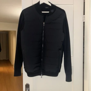 Svart jacka från Massimo Dutti - Snygg svart jacka från Massimo Dutti med dragkedja framtill. Jackan har en quiltad design på framsidan och långa ärmar. Perfekt för en stilren look. Köpt för 899, funkar för storlek s och m. Pris kan diskuteras privat.