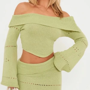 Grön offshoulder stickad topp - Säljer en snygg grön offshoulder stickad topp från plt. Toppen har långa ärmar med dekorativa hål och en croppad design. Perfekt för en trendig look! 