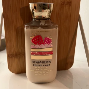 Strawberry Pound Cake Body Lotion - En härlig body lotion från Bath & Body Works med doft av jordgubbstårta. Innehåller sheasmör och kokosolja för att ge 24 timmars återfuktning. Flaskan rymmer 236 ml och har en söt design med jordgubbar och tårta på framsidan.