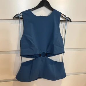 Blå topp från Zara - Snygg blå topp från Zara med en unik design. Toppen har en midjebanddetalj och är ärmlös, vilket ger en modern och stilren look. Perfekt för att lyfta vilken outfit som helst. 💙(helt ny med prislapp) original pris 329