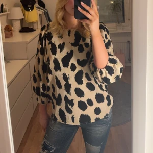 Beige och svart blus med leopardmönster - Säljer en snygg beige blus med svart leopardmönster. Blusen har trekvartsärmar och en lös passform.