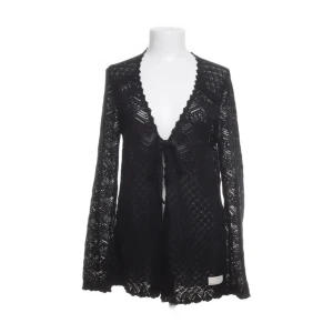 Spetskofta från Odd Molly - Elegant svart spetskofta med långa ärmar och knytband framtill. Perfekt för att lägga till en touch av stil till din outfit. Koftan har ett vackert mönster och är lätt och luftig.