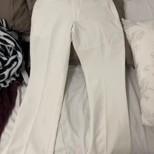 Vita kostymbyxor från BikBok - Snygga vita kostymbyxor från BikBok med en elegant och stilren design. Byxorna har en rak passform och är perfekta för en chic look. Köpta från Bikbok. Har slits där nere.