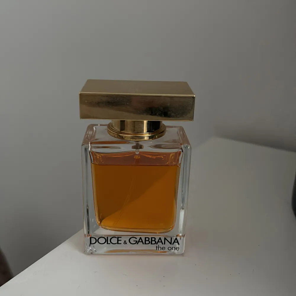 Säljer en elegant parfym från Dolce & Gabbana, The One. Flaskan är rektangulär med en gyllene kork och innehåller en varm, bärnstensfärgad doft. Perfekt för den som vill ha en sofistikerad och tidlös doft. 50 Ml. Perfume.