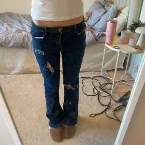 Mörkblå bootcut jeans med slitningar - Snygga mörkblå lågmidjade bootcut jeans med coola slitningar på benen 