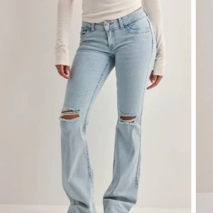 Ljusblå bootcut jeans med slitningar - Snygga ljusblå lågmidjade jeans från Nelly med bootcut-stil och slitningar på knäna. Uppklippta så de passar någon som är ungefär 160-165.  Nypris: 699 Nyskick
