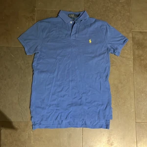 Blå pikétröja från Ralph Lauren - Säljer en klassisk blå pikétröja från Ralph Lauren i storlek S. Ej använd så dags att den får ny ägare. Skicka privat för funderingar. Riktig 2010 känsla på den. Pris kan diskuteras vid snabb affär.