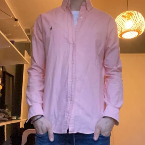 Rosa skjorta från Ralph Lauren - Snygg rosa skjorta från Ralph Lauren i slim fit. Skjortan har långa ärmar och knappar framtill. Perfekt för en stilren look.
